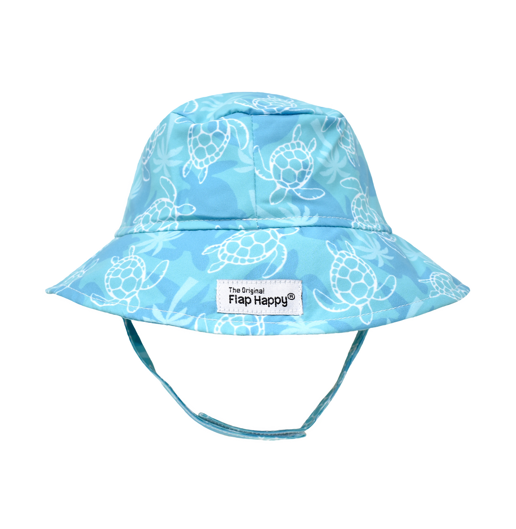 UPF 50+ Bucket Hat - Tortuga Bay. Teal hat with dark teal turtle silhouettes, soft green palm trees, and white linework turtles. Velcro chin strap.