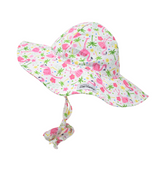 UPF 50+ Floppy Hat - Flamingo Party. White hat with  light and dark pink flamingos, green palm trees, pink and yellow hibiscus flowers, and multicolor polka dots. Ties around neck.
