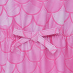 Close-up of a pink fabric product with a mermaid scale pattern and a matching fabric bow at the center.