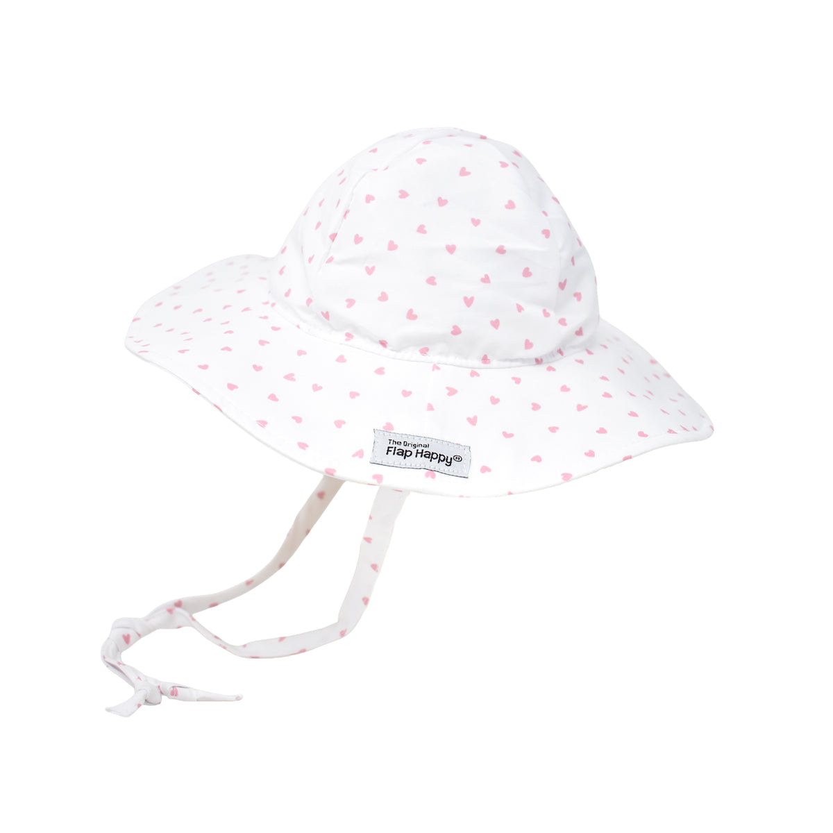 A white floppy sun hat with a small pink heart pattern, featuring a wide brim, adjustable tie that extends from the sides and ties under the chin. Features a small “The Original Flap Happy” brand label on the brim.